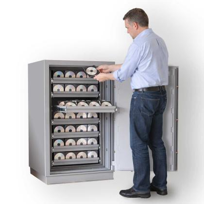 Person legt Datenträger in Datensicherungstresor